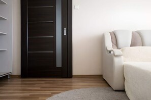 Une chambre moderne avec une armoire en bois foncé, un canapé blanc et un tapis gris.