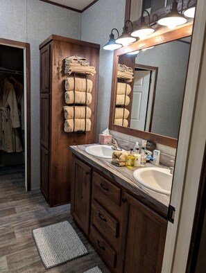 Een badkamer met houten kastjes, een dubbele wastafel en een spiegel met verlichting.