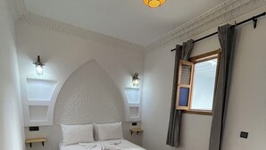 Een slaapkamer met een bed, een vloer met een patroon, decoratieve plafond en wandlampen.