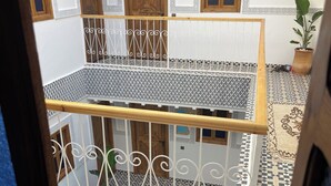 Een gebouw met twee verdiepingen, een balkon, versierde vloertegels en houten deuren.