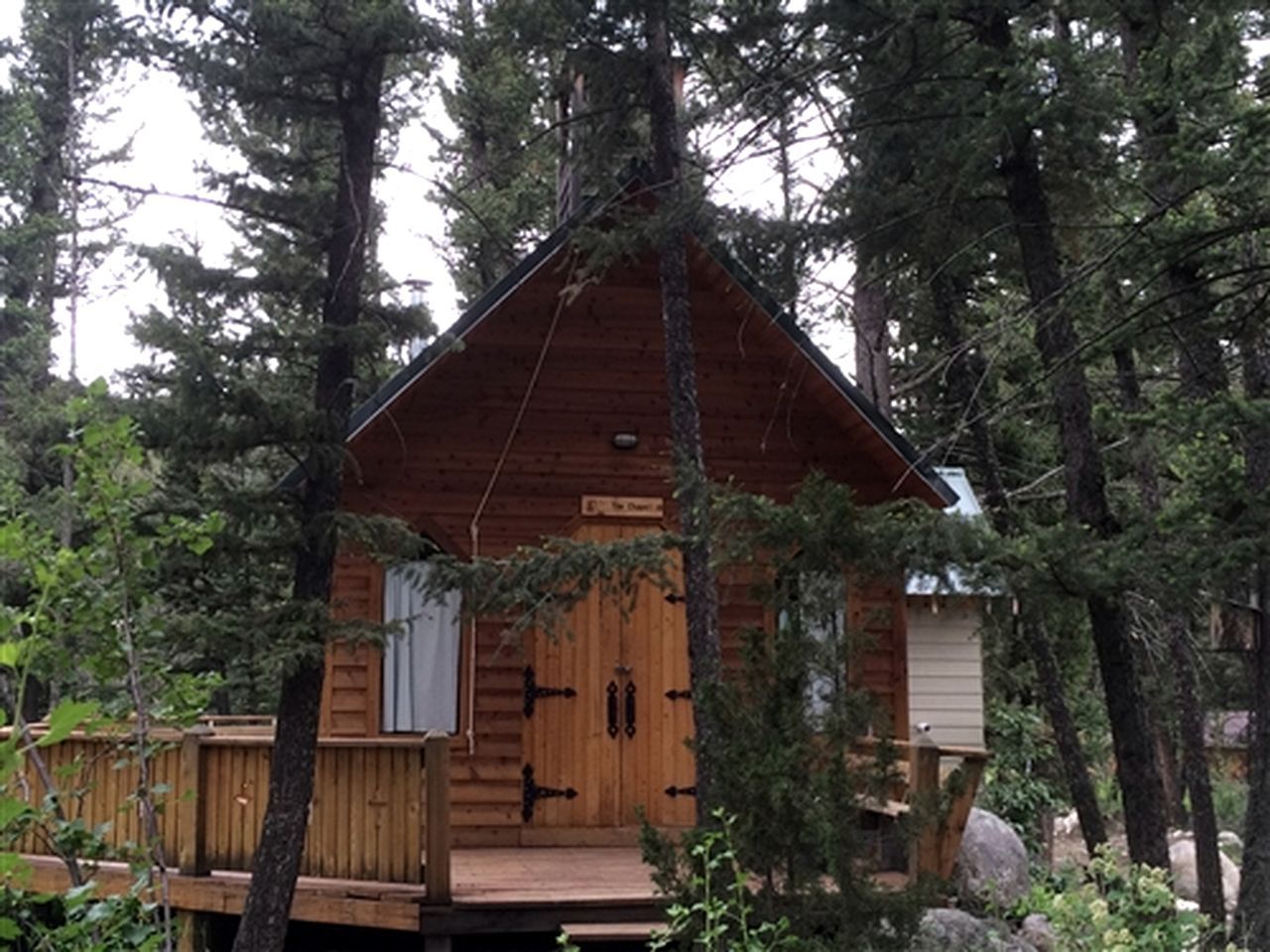A cabin with a wooden exterior, a front door, and a small porch.