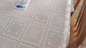 A dining table with a lace tablecloth, a chair, a small table with a glass, and a sofa with a quilted cover. - Beachfront Escape with Breezy Views in North Truro, Massachusetts (North Truro)