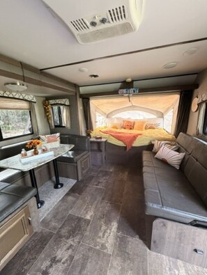 Ein kompaktes Wohnmobil-Interieur mit Küchenzeile, Essbereich und Schlafbereich.
