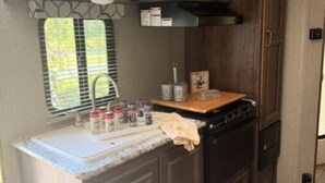 Une cuisine de taille réduite équipée d’un four à micro-ondes, d’une cuisinière et de placards.