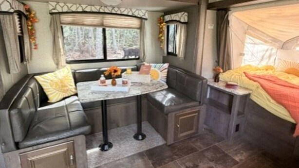 Un intérieur de camping-car compact comprenant un coin salon, une petite table et un lit avec un auvent.