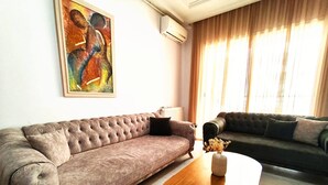 Un salon avec deux canapés, une table basse et un tableau accroché au mur.