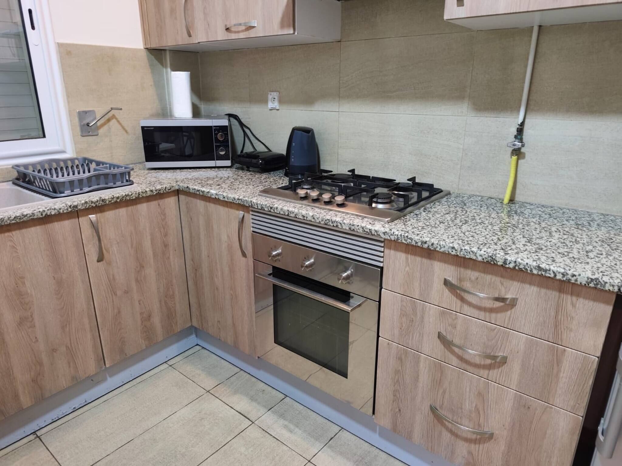 A kitchen with wooden cabinets, a microwave, a gas stove, and an oven.