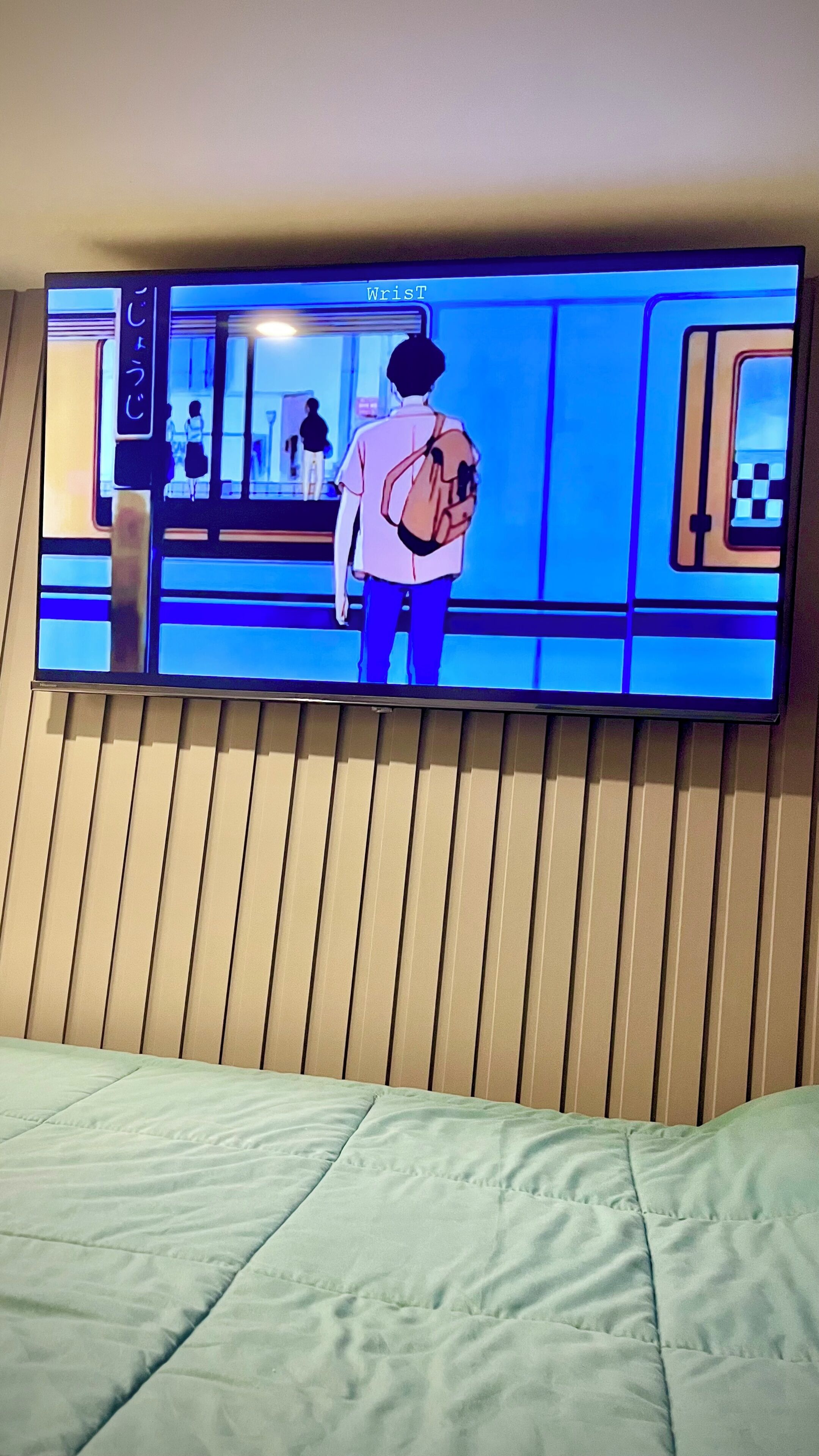A television mounted on a wall displaying a scene with a person carrying a backpack.