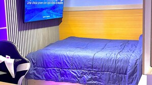 Huoneessa on sänky, työpöytä ja seinälle asennettu televisio.