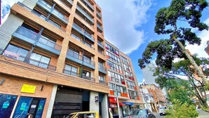 Um edifício de vários andares com design moderno, com varandas e grandes janelas.
