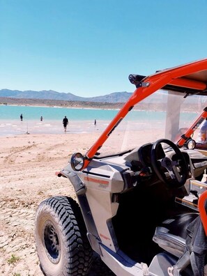 Un vehicle de disseny robust al costat de la platja, amb volant i quadre de comandament visible.