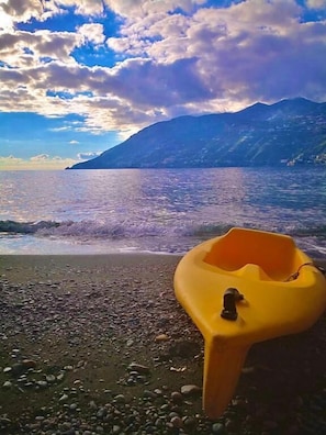 A kayak on a pebbly beach with a mountain in the background. - Casa Palomba 41 (Minori)