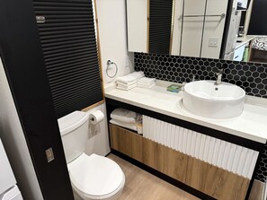 A compact bathroom with a toilet, sink, and storage cabinets.