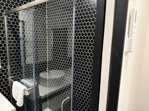 Une salle de bain avec une paroi en verre, un porte-serviettes et des toilettes.