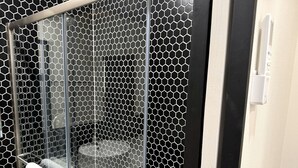Ein Badezimmer mit Glasabtrennung, Handtuchhalter und Toilette.