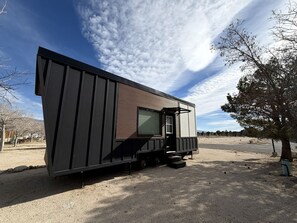 Une maison mobile moderne, de plain-pied, avec un toit plat, une grande fenêtre et un petit espace porche.