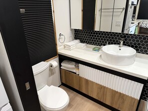 A compact bathroom with a toilet, sink, and storage cabinets.