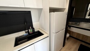 Eine kleine Küche mit weißen Schränken, einer schwarzen Arbeitsplatte und einem eingebauten Backofen.