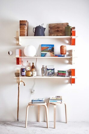 A bookshelf with books, a kettle, and a vase.