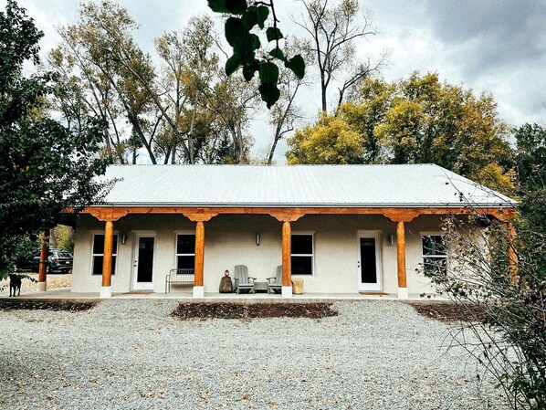 A building with a porch, two chairs, and a gravel driveway.