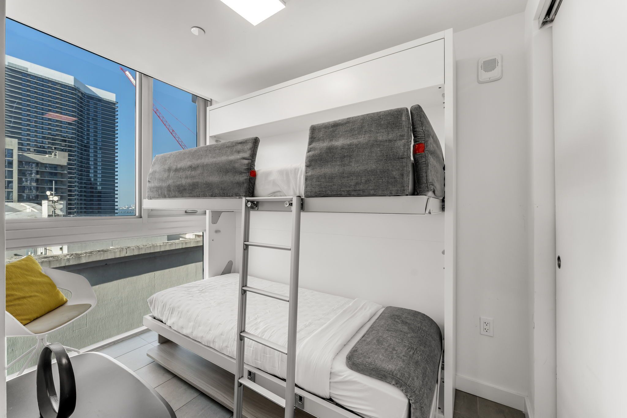 Habitación con literas y vista a un edificio y una grúa.
