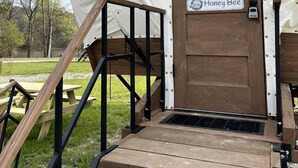 Een overdekte constructie met een houten deur waarop 'Honey Bee' staat, een houten hellingbaan en een picknicktafel.
