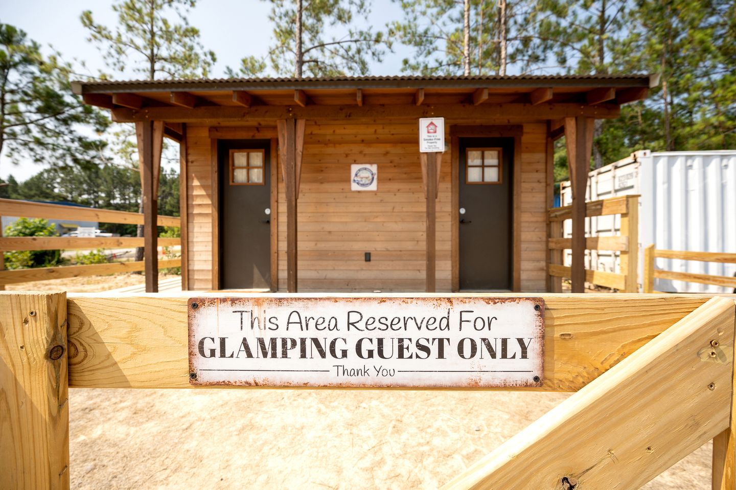 A wooden structure with a sign stating 'This Area Reserved For GLAMPING GUEST ONLY.'