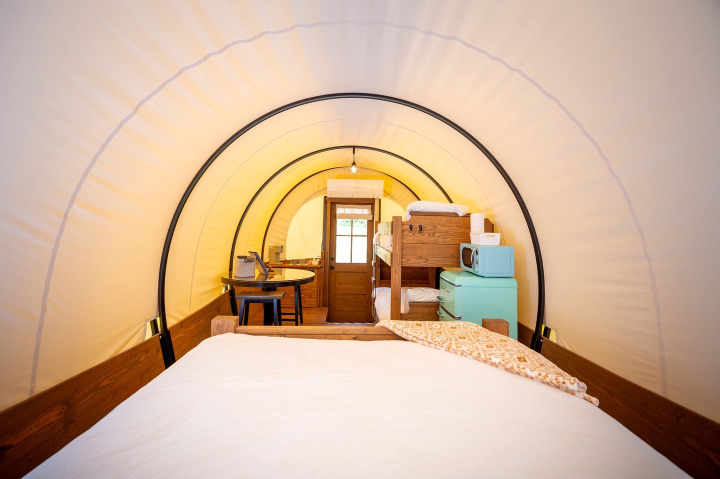 A tent with a bed, a table, and a kitchenette area.