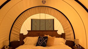 Una cama con cabecera de madera, dos mesitas de noche con lámparas y un reloj digital.