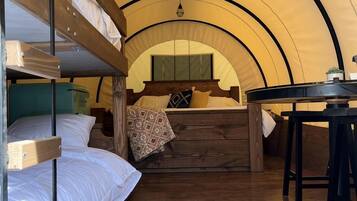 A tent with bunk beds, a table, and a hanging light fixture.