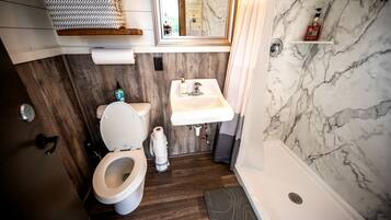 A compact bathroom with a toilet, sink, and shower.