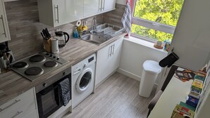 Een moderne keuken met een inbouw wasmachine, een spoelbak en een raam met uitzicht op groen.