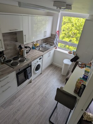 Eine moderne Küche mit Einbauwaschmaschine, Spüle und Fenster mit Blick auf Grünflächen.