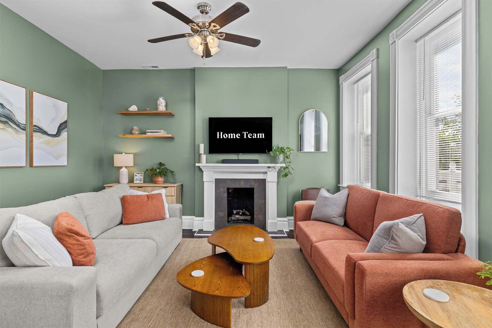Ein Wohnzimmer mit Kamin, zwei Sofas, einem Fernseher und einem Deckenventilator.