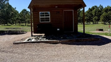 A wooden cabin with a porch, a door, and a window.