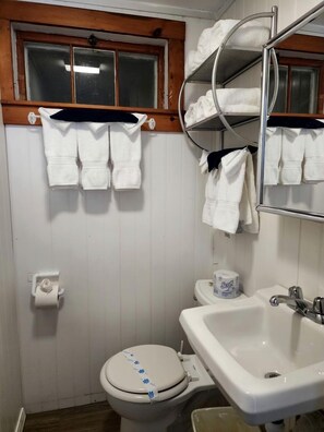Et badeværelse med toilet, vask, håndklædestang og et vindue.