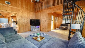 Ein Holzinnenraum mit einer Couch, einem Fernseher und einer Treppe.