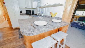 Eine Küche mit einer Granit-Arbeitsplatte, weißen Schränken, einer Holz-Kochinsel inklusive Barhocker und einem sichtbaren Spülbecken.