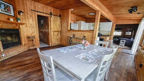 Ein Holzinterieur mit Esstisch, Stühlen, Kamin und Küchenbereich.