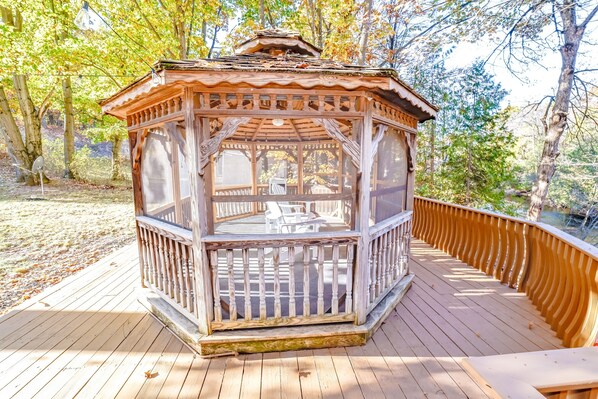 A wooden gazebo with a glass enclosure, surrounded by a wooden deck.