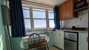 Eine Küche mit Fenster, Stuhl, Tisch und Kühlschrank.