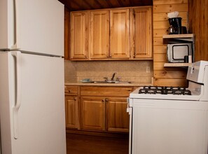 A kitchen with wooden cabinets, a white refrigerator, a stove, and a microwave. - Cabin #2 (Flagstaff)