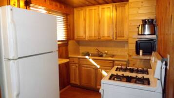 Une cuisine avec des meubles de rangement en bois, un réfrigérateur blanc, une cuisinière et un four à micro-ondes.