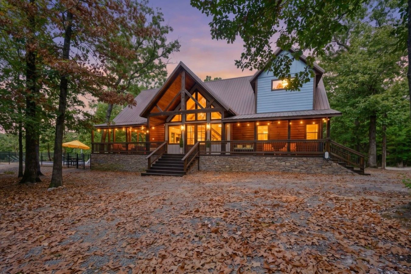 A lodge with a prominent wooden structure, a stone foundation, and a porch with lights.