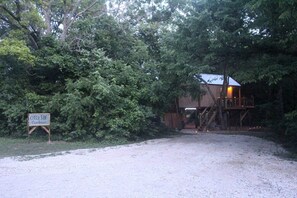 A rustic cabin with a wooden deck and a staircase leading to a second level. - Enchanting Pecan Treehouse with Creek Views near Forestburg, Texas (Forestburg)