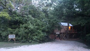 Une cabane rustique dotée d’une terrasse en bois et d’un escalier menant à un deuxième niveau.
