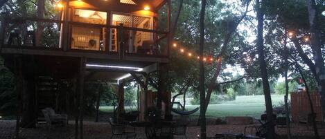 Une cabane en bois dotée d’un balcon, d’un espace salon extérieur et de guirlandes lumineuses.
