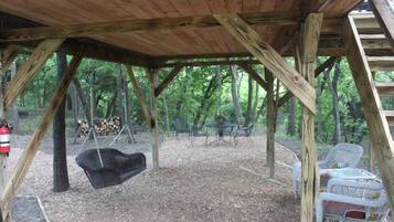 A wooden structure with a swing, outdoor seating, and a fire extinguisher.
