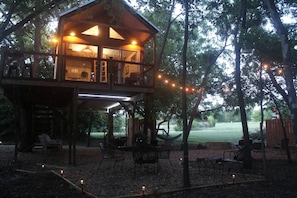Uma cabana de madeira com varanda, área de estar externa e luzes de Natal.