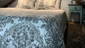 Une chambre à coucher avec un lit, des oreillers, une table de chevet et un plafond avec des poutres en bois.